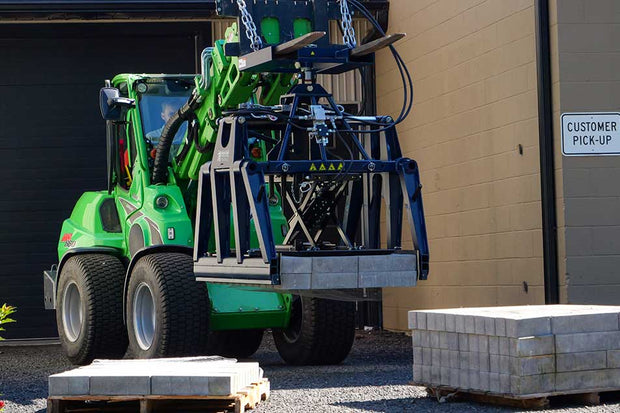 Green forklift with a pallet jack attachment in front of a building with a 'Customer Pick-Up' sign.