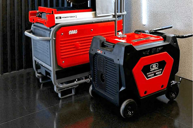 Two power generators, one red and one black, on a reflective surface.